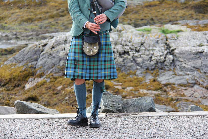 A kilted Highlander playing the bagpipes.